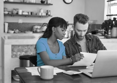 Couple looking at paperwork while sitting with their laptop